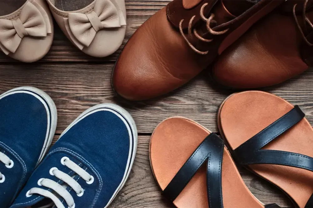 Women's shoes of different seasons on the wooden floor. Top view of sandals, boots, sneakers, ballet shoes.